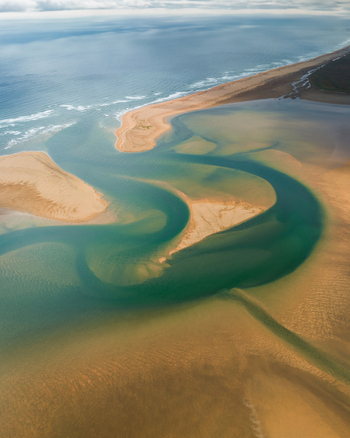 Aerial view of serpentine waterways carve through the golden sands where the ocean s blue embraces the shore Rauðisandur Vesturbyggð Iceland. Aerial view of serpentine waterways carve through the golden sands where the ocean s blue embraces the shore Rauðisandur Vesturbyggð Iceland.