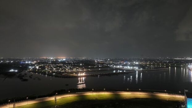 Aerial view of the illuminated Pantai Indah Kapuk 2 waterfront at night with city lights reflecting on the water in Kecamatan Penjaringan Banten Indonesia. Aerial view of the illuminated Pantai Indah Kapuk 2 waterfront at night with city lights reflecting on the water in Kecamatan Penjaringan Banten Indonesia.