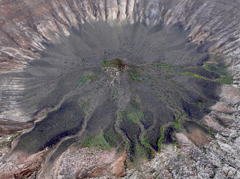Aerial view of a volcanic crater with dark lava flows and sparse green vegetation in Lanzarote. Aerial view of a volcanic crater with dark lava flows and sparse green vegetation in Lanzarote.