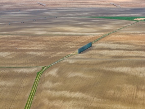 Aerial view of a dirt road cutting through vast patterned fields creating a stark contrast between the natural earth tones and the linear path Neuf Brisach Grand Est France.