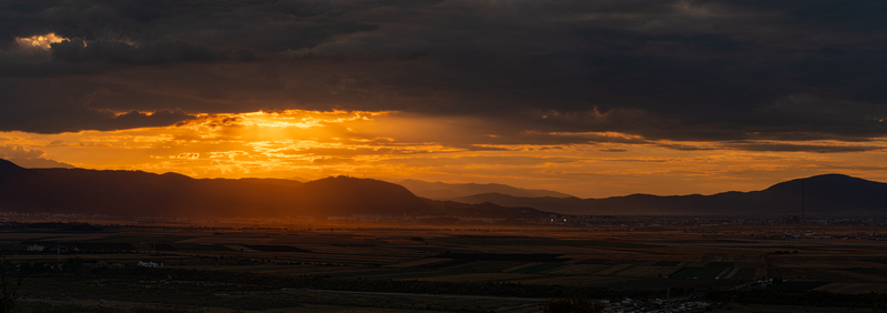 View of a dramatic sunset over the mountains and fields surrounding the city of Brasov Brasov Romania. View of a dramatic sunset over the mountains and fields surrounding the city of Brasov Brasov Romania.