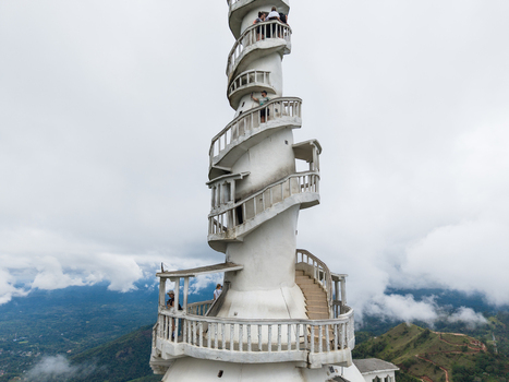 Aerial view of Ambuluwawa Tower with its unique spiral staircase and tourists on balconies overlooking misty mountains in Gampola Central Province Sri Lanka. Aerial view of Ambuluwawa Tower with its unique spiral staircase and tourists on balconies overlooking misty mountains in Gampola Central Province Sri Lanka.