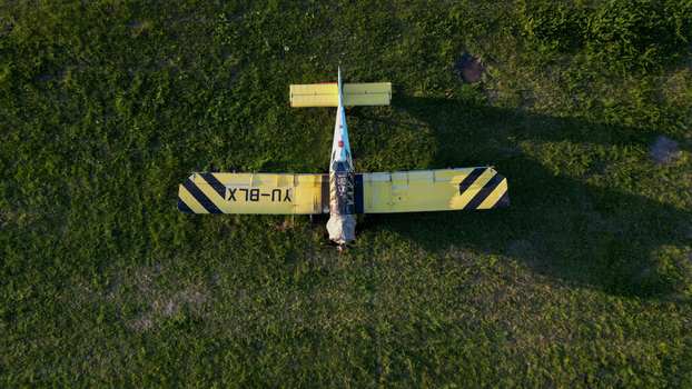 Serbia 03 September 2023 Aerial view of a yellow and black propeller plane parked on a grassy field.