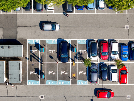 Aerial view of an electric vehicle charging station with parked cars and EV symbols on the asphalt in Turin Piedmont Italy. Aerial view of an electric vehicle charging station with parked cars and EV symbols on the asphalt in Turin Piedmont Italy.