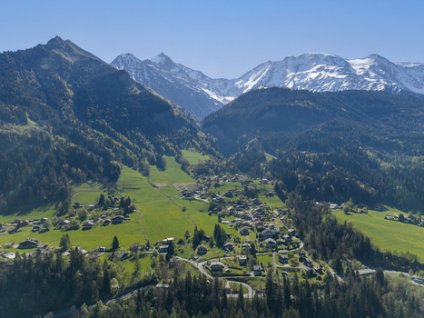 Saint Gervais les Bains France 30 April 2026 Aerial view of the alpine village of Saint Gervais les Bains surrounded by lush green meadows and snow capped mountain peaks under a clear blue sky.