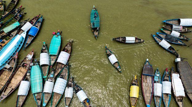 Aerial view of Baish Mowza Sarak Bazar with numerous traditional wooden boats moored on the river in Nabinagar Chittagong Division Bangladesh. Aerial view of Baish Mowza Sarak Bazar with numerous traditional wooden boats moored on the river in Nabinagar Chittagong Division Bangladesh.