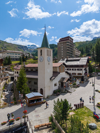 Aerial view of the church in the alpine village of Breuil Cervinia with surrounding mountains stone buildings and a small stream in Breuil Cervinia Aosta Valley Italy. Aerial view of the church in the alpine village of Breuil Cervinia with surrounding mountains stone buildings and a small stream in Breuil Cervinia Aosta Valley Italy.