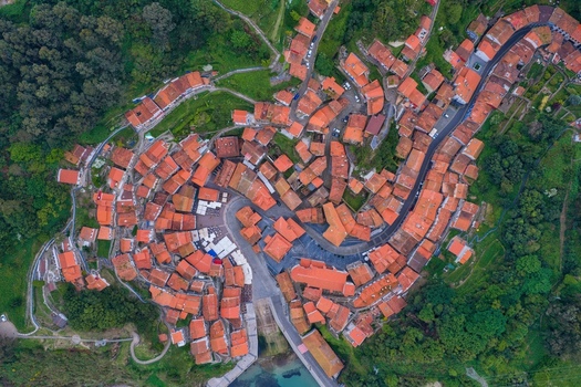 Aerial view of the colorful houses and terracotta rooftops of the historic village nestled in a lush green valley in Cudillero Asturias Spain. Aerial view of the colorful houses and terracotta rooftops of the historic village nestled in a lush green valley in Cudillero Asturias Spain.