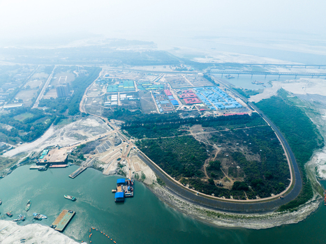 Aerial view of the riverbank area featuring industrial development construction site and small boats on the water in Tangail Dhaka Division Bangladesh. Aerial view of the riverbank area featuring industrial development construction site and small boats on the water in Tangail Dhaka Division Bangladesh.
