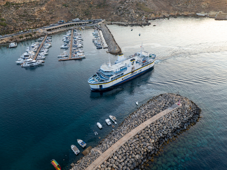 Mgarr Harbor Malta 08 June 2025 Aerial view of a large ferry navigating the tranquil deep blue waters juxtaposed against the clustered yachts in the marina. Mgarr Harbor Malta 08 June 2025 Aerial view of a large ferry navigating the tranquil deep blue waters juxtaposed against the clustered yachts in the marina.