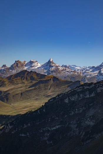 View of the snow capped peaks of the Swiss Alps rising above rocky slopes and green valleys under a clear blue sky in Airolo Ticino Switzerland. View of the snow capped peaks of the Swiss Alps rising above rocky slopes and green valleys under a clear blue sky in Airolo Ticino Switzerland.