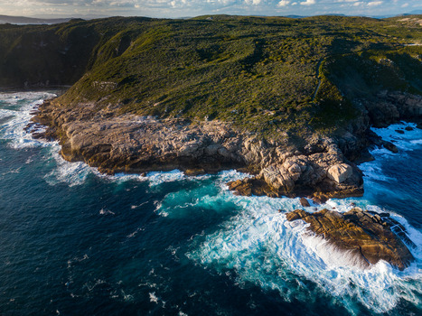 Aerial view of the rugged coastline of Torndirrup National Park with crashing waves against granite cliffs and dense coastal vegetation in Torndirrup Western Australia Australia. Aerial view of the rugged coastline of Torndirrup National Park with crashing waves against granite cliffs and dense coastal vegetation in Torndirrup Western Australia Australia.