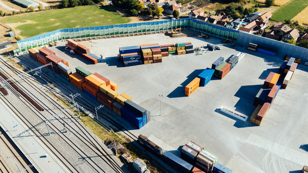 Indjija Serbia 24 August 2026 Aerial view of a freight yard featuring colorful shipping containers stacked on a gravel lot adjacent to railway tracks and industrial infrastructure.