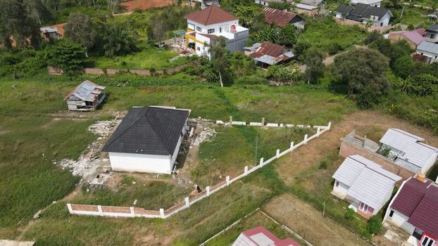 Aerial view of residential houses with dark roofs and white walls surrounded by green fields and fences in Palembang South Sumatra Indonesia. Aerial view of residential houses with dark roofs and white walls surrounded by green fields and fences in Palembang South Sumatra Indonesia.