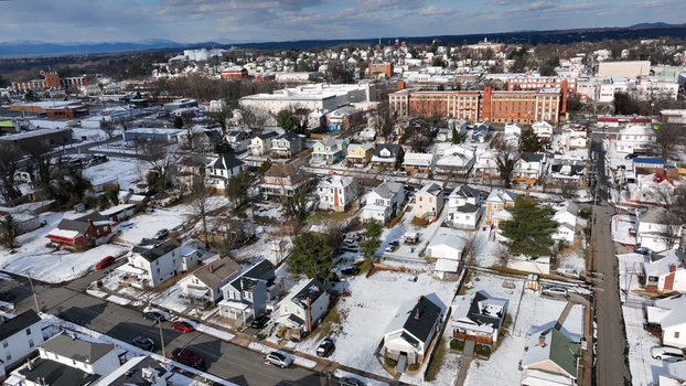 Aerial view of a residential neighborhood covered in light snow with houses streets and distant mountains under a clear sky in Lynchburg Virginia United States. Aerial view of a residential neighborhood covered in light snow with houses streets and distant mountains under a clear sky in Lynchburg Virginia United States.