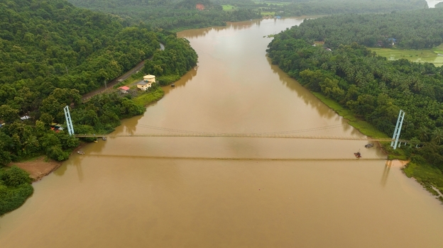 Aerial view of the suspension bridge spanning the Sharavathi river surrounded by lush green forests and palm trees in Honnavar Karnataka India.
