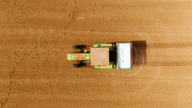 Aerial view of a lone green tractor leaves patterned tracks in the soft brown earth of a vast field Sremska Mitrovica Vojvodina Serbia. Aerial view of a lone green tractor leaves patterned tracks in the soft brown earth of a vast field Sremska Mitrovica Vojvodina Serbia.