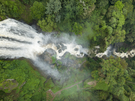 Aerial view of cascading Curugsewu Waterfall through lush greenery a misty veil shrouding the vibrant landscape Kendal Regency Central Java Indonesia. Aerial view of cascading Curugsewu Waterfall through lush greenery a misty veil shrouding the vibrant landscape Kendal Regency Central Java Indonesia.