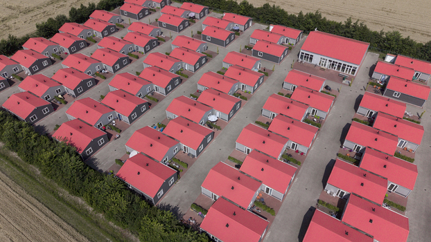 Aerial view of the prefabricated housing for migrant and seasonal workers featuring rows of identical houses with bright red roofs and paved walkways in Swifterbant Flevoland Netherlands. Aerial view of the prefabricated housing for migrant and seasonal workers featuring rows of identical houses with bright red roofs and paved walkways in Swifterbant Flevoland Netherlands.