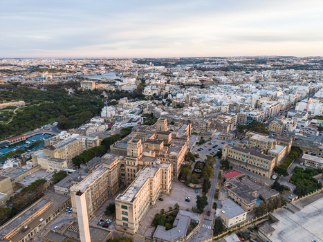 Aerial view of a historic limestone building complex and dense urban rooftops under a soft evening sky Malta. Aerial view of a historic limestone building complex and dense urban rooftops under a soft evening sky Malta.