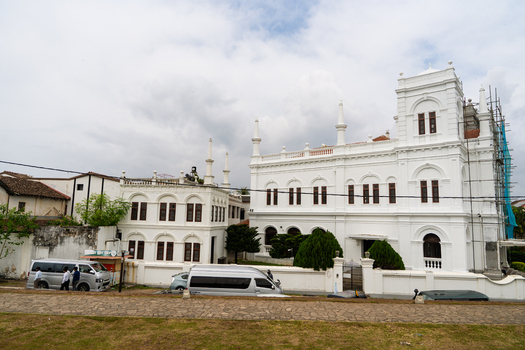 View of the historic Meeran Jumma Mosque with its white facade and minarets under a cloudy sky in Galle Southern Province Sri Lanka.