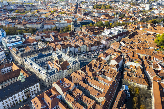 Aerial view of terracotta rooftops contrasting with the bright blue sky over the Hauptplatz and the clock tower of the Grazer Rathaus Graz Styria Austria.