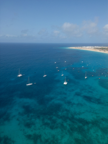 Aerial view of turquoise waters with anchored catamarans and sailboats near the sandy coastline and town buildings Santa Maria Sal Cabo Verde. Aerial view of turquoise waters with anchored catamarans and sailboats near the sandy coastline and town buildings Santa Maria Sal Cabo Verde.