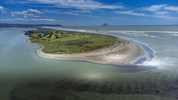 Aerial view of Ohope Spit with its sandy beach grassy dunes and calm waters under a clear blue sky in Ohope Bay of Plenty Region New Zealand.