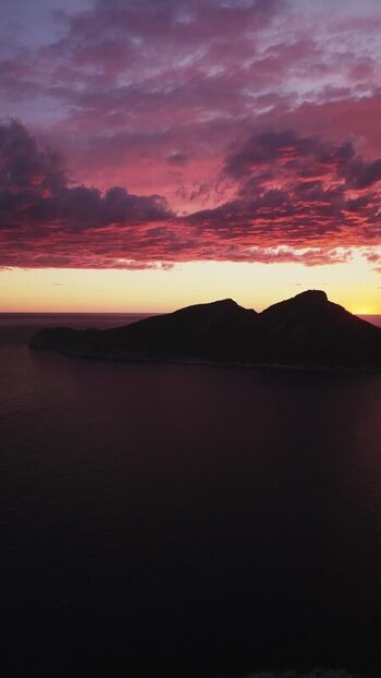Aerial view of a rocky island silhouette at sunset Spain.