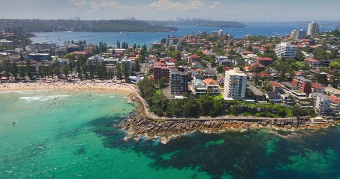 Aerial view of the coastline at Manly Beach with turquoise water sandy shore residential buildings and rocky cliffs in Sydney New South Wales Australia. Aerial view of the coastline at Manly Beach with turquoise water sandy shore residential buildings and rocky cliffs in Sydney New South Wales Australia.
