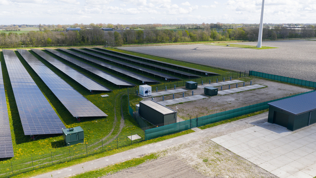 Aerial view of rows of solar panels in a solar farm surrounded by green fields and trees under a bright sky Warmenhuizen North Holland Netherlands. Aerial view of rows of solar panels in a solar farm surrounded by green fields and trees under a bright sky Warmenhuizen North Holland Netherlands.