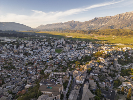 Aerial view of the historic city of Gjirokaster featuring stone houses the fortress and the surrounding mountainous landscape in Gjirokaster Gjirokaster County Albania. Aerial view of the historic city of Gjirokaster featuring stone houses the fortress and the surrounding mountainous landscape in Gjirokaster Gjirokaster County Albania.