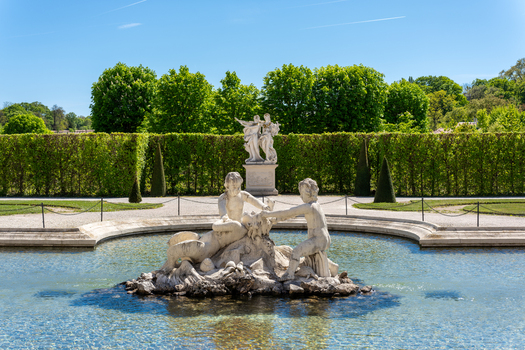 View of the ornate fountain and sculptures in the manicured gardens of the Belvedere Palace under a clear blue sky in Vienna Vienna Austria. View of the ornate fountain and sculptures in the manicured gardens of the Belvedere Palace under a clear blue sky in Vienna Vienna Austria.