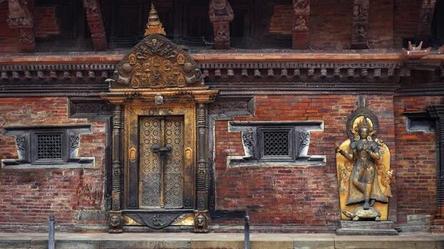 View of an ornate golden door and deity statue on a temple Nepal.