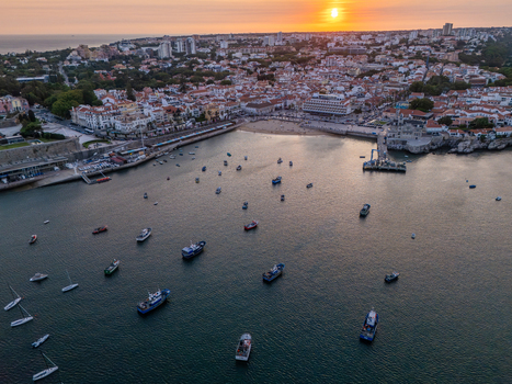 Aerial view of the coastal town of Cascais with fishing boats anchored in the bay historic buildings and a sunset sky in Cascais Lisboa Portugal. Aerial view of the coastal town of Cascais with fishing boats anchored in the bay historic buildings and a sunset sky in Cascais Lisboa Portugal.