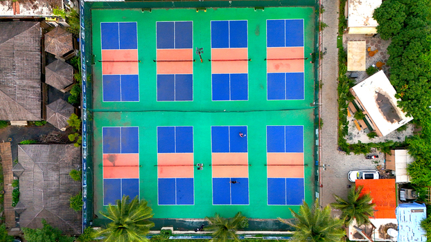Aerial view of pickleball courts with blue and orange markings on a green surface surrounded by palm trees and buildings near Olpad Road in Surat Gujarat India. Aerial view of pickleball courts with blue and orange markings on a green surface surrounded by palm trees and buildings near Olpad Road in Surat Gujarat India.