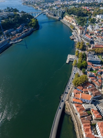 Aerial view of Viaduto do Cais das Pedras spanning the Douro River with urban rooftops and historic architecture along the waterfront in Porto Porto Portugal.