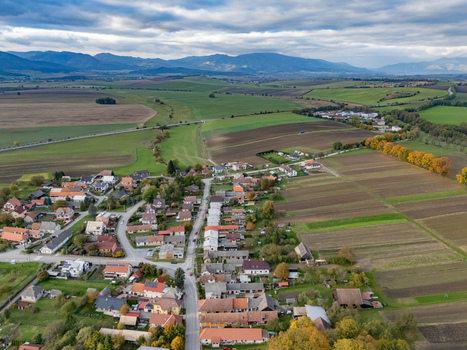 Aerial view of a tranquil village s warm roofs contrasting with autumnal fields and distant mountains under a cloudy sky Mosovce Zilina Region Slovakia. Aerial view of a tranquil village s warm roofs contrasting with autumnal fields and distant mountains under a cloudy sky Mosovce Zilina Region Slovakia.