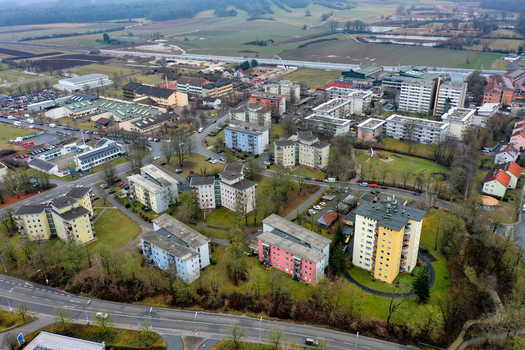 Aerial view of residential apartment buildings green spaces and surrounding fields under a soft daylight Forchheim Bavaria Germany.