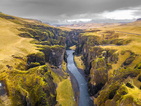 Aerial view of the river snaking through the deep gorge where moss covered cliffs meet the sky under a brooding dramatic sky Fjaðrárgljúfur Skaftárhreppur Iceland. Aerial view of the river snaking through the deep gorge where moss covered cliffs meet the sky under a brooding dramatic sky Fjaðrárgljúfur Skaftárhreppur Iceland.