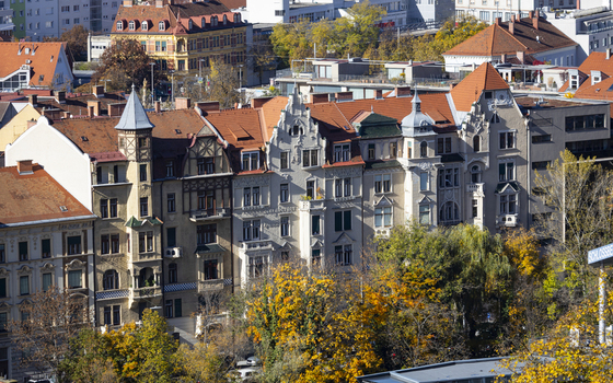 View of historic buildings with red tiled roofs nestled amongst autumn foliage creating a tapestry of warm hues against the urban backdrop Graz Styria Austria. View of historic buildings with red tiled roofs nestled amongst autumn foliage creating a tapestry of warm hues against the urban backdrop Graz Styria Austria.