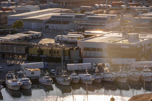 Aerial view of Ancona Port with fishing boats docked in the harbor industrial warehouses and parked semi trucks in the background in Ancona Marche Italy. Aerial view of Ancona Port with fishing boats docked in the harbor industrial warehouses and parked semi trucks in the background in Ancona Marche Italy.