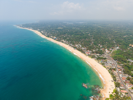 Aerial view of the tropical coastline featuring sandy beaches turquoise ocean waves and lush green vegetation in Dodanduwa Southern Province Sri Lanka. Aerial view of the tropical coastline featuring sandy beaches turquoise ocean waves and lush green vegetation in Dodanduwa Southern Province Sri Lanka.