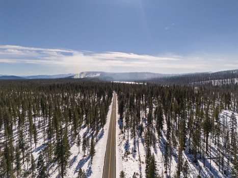Aerial view of a road cutting through a snowy forest with signs of a recent wildfire and smoke in the distance in Oregon United States. Aerial view of a road cutting through a snowy forest with signs of a recent wildfire and smoke in the distance in Oregon United States.