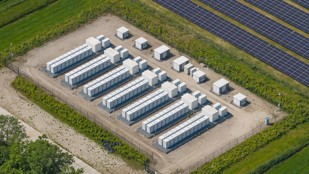 Aerial view of a battery energy storage system with rows of white containers located next to a large solar panel farm in Wanneperveen Overijssel Netherlands. Aerial view of a battery energy storage system with rows of white containers located next to a large solar panel farm in Wanneperveen Overijssel Netherlands.