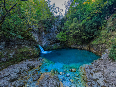 Aerial view of Blue Eye Theth a natural spring with vibrant turquoise water surrounded by rocky cliffs and lush green forest in Theth Shkoder County Albania. Aerial view of Blue Eye Theth a natural spring with vibrant turquoise water surrounded by rocky cliffs and lush green forest in Theth Shkoder County Albania.