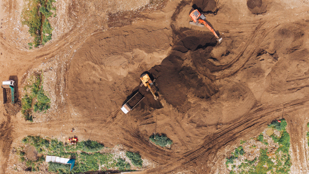 Aerial view of excavators and dump trucks working on a construction site with piles of earth and tire tracks in Chennai India. Aerial view of excavators and dump trucks working on a construction site with piles of earth and tire tracks in Chennai India.