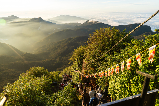View of Adam s Peak with pilgrims climbing the steep path decorated with Buddhist flags at sunrise Ratnapura Sabaragamuwa Province Sri Lanka. View of Adam s Peak with pilgrims climbing the steep path decorated with Buddhist flags at sunrise Ratnapura Sabaragamuwa Province Sri Lanka.