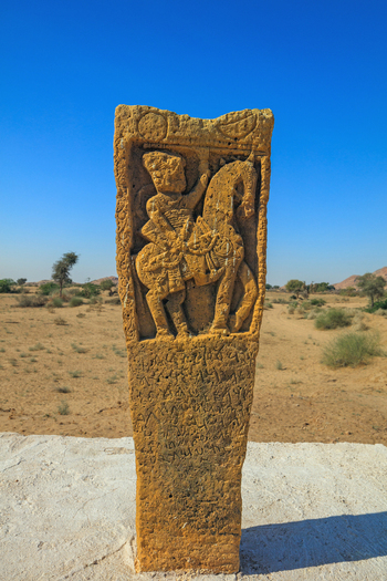 View of an ancient carved hero stone monument depicting a warrior on horseback standing in the arid desert landscape of Nagarparkar Sindh Pakistan.