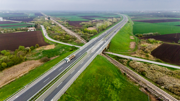 Aerial view of a long highway cutting through vibrant green fields contrasting with the dark soil of cultivated lands Sremska Mitrovica Vojvodina Serbia. Aerial view of a long highway cutting through vibrant green fields contrasting with the dark soil of cultivated lands Sremska Mitrovica Vojvodina Serbia.